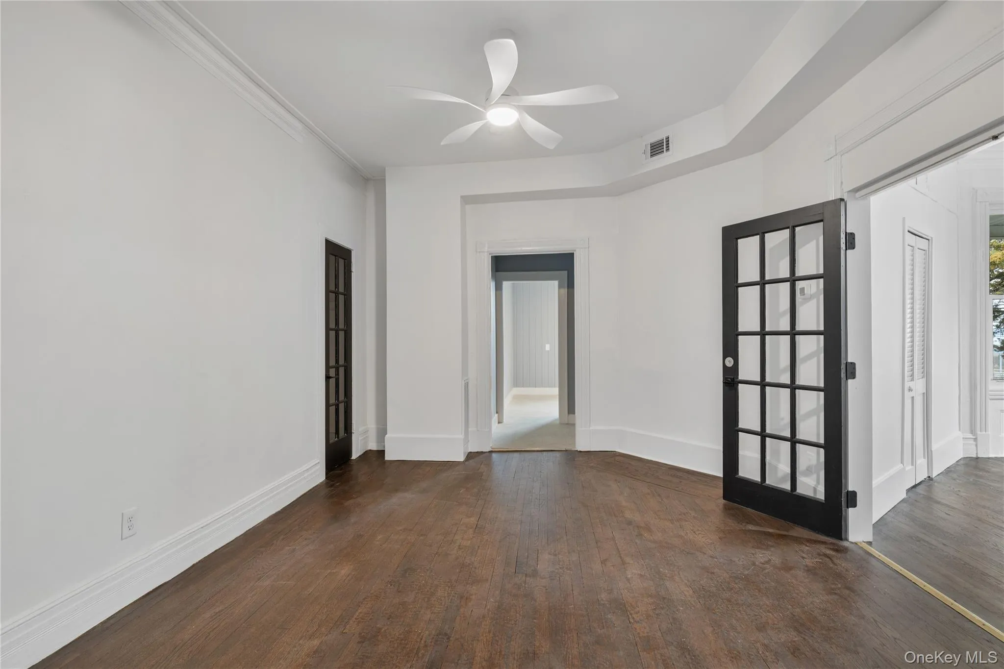 Empty room with wood finished floors, baseboards, a ceiling fan, and visible vents Empty room with wood finished floors, baseboards, a ceiling fan, and visible vents