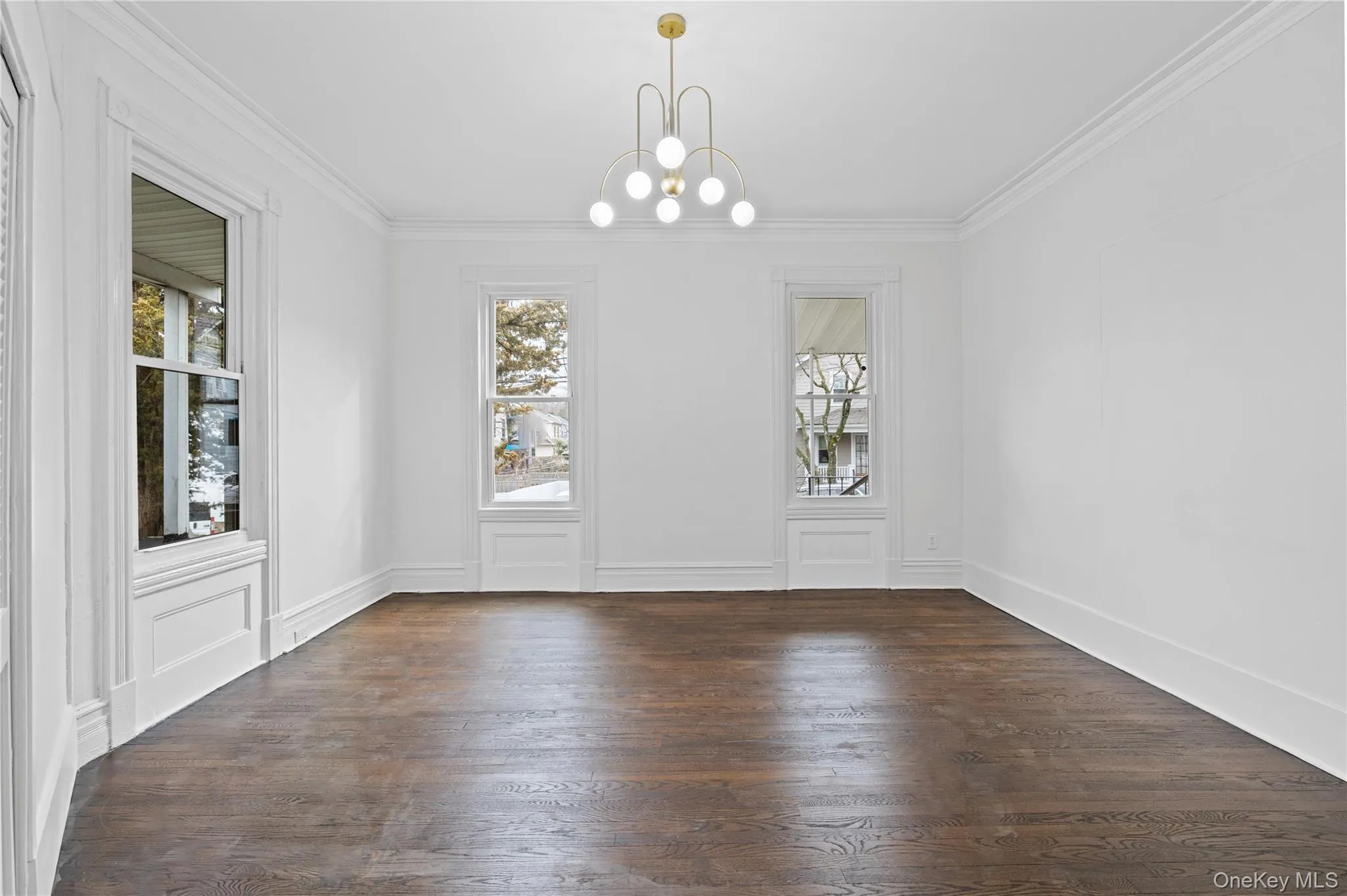 Unfurnished dining area featuring dark wood-style flooring, ornamental molding, plenty of natural light, and a chandelier Unfurnished dining area featuring dark wood-style flooring, ornamental molding, plenty of natural light, and a chandelier