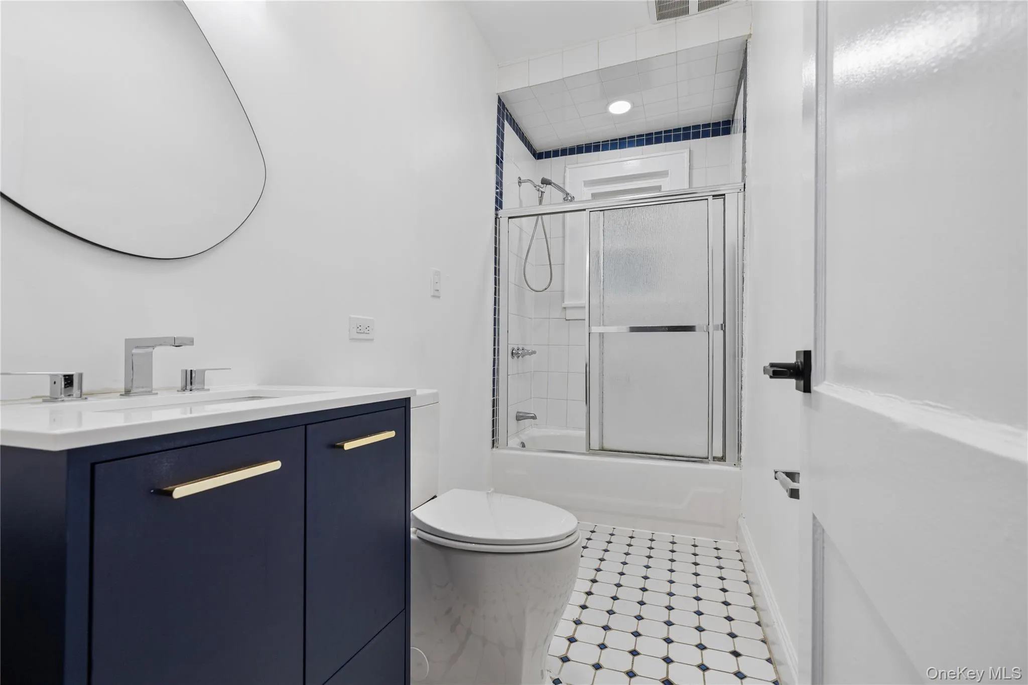 Full bathroom with toilet, shower / bath combination with glass door, vanity, and visible vents Full bathroom with toilet, shower / bath combination with glass door, vanity, and visible vents