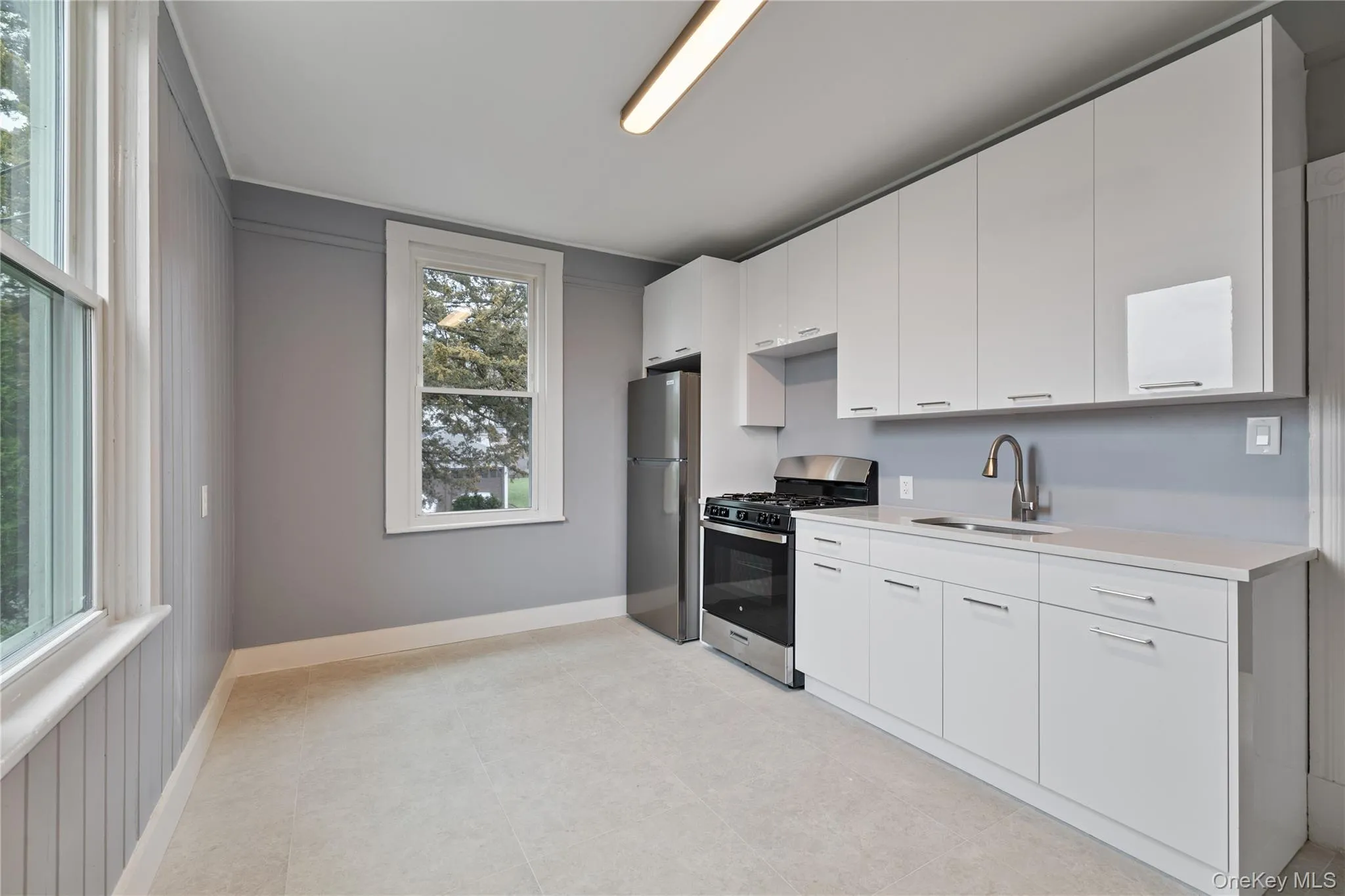 Kitchen featuring a sink, light countertops, white cabinetry, and stainless steel appliances Kitchen featuring a sink, light countertops, white cabinetry, and stainless steel appliances