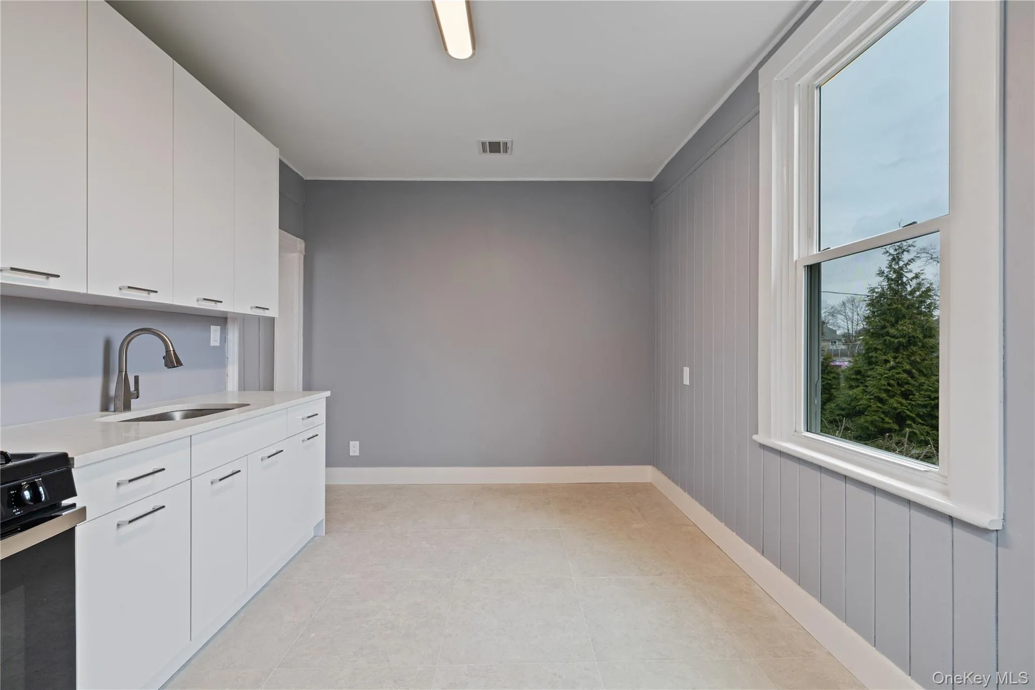 Kitchen with baseboards, a sink, light countertops, white cabinetry, and range Kitchen with baseboards, a sink, light countertops, white cabinetry, and range