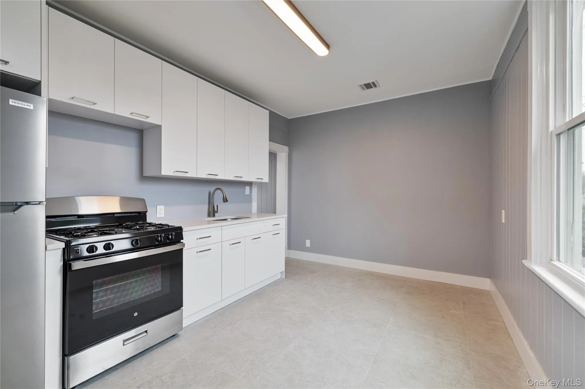 Kitchen with white cabinets, visible vents, light countertops, a sink, and stainless steel appliances Kitchen with white cabinets, visible vents, light countertops, a sink, and stainless steel appliances