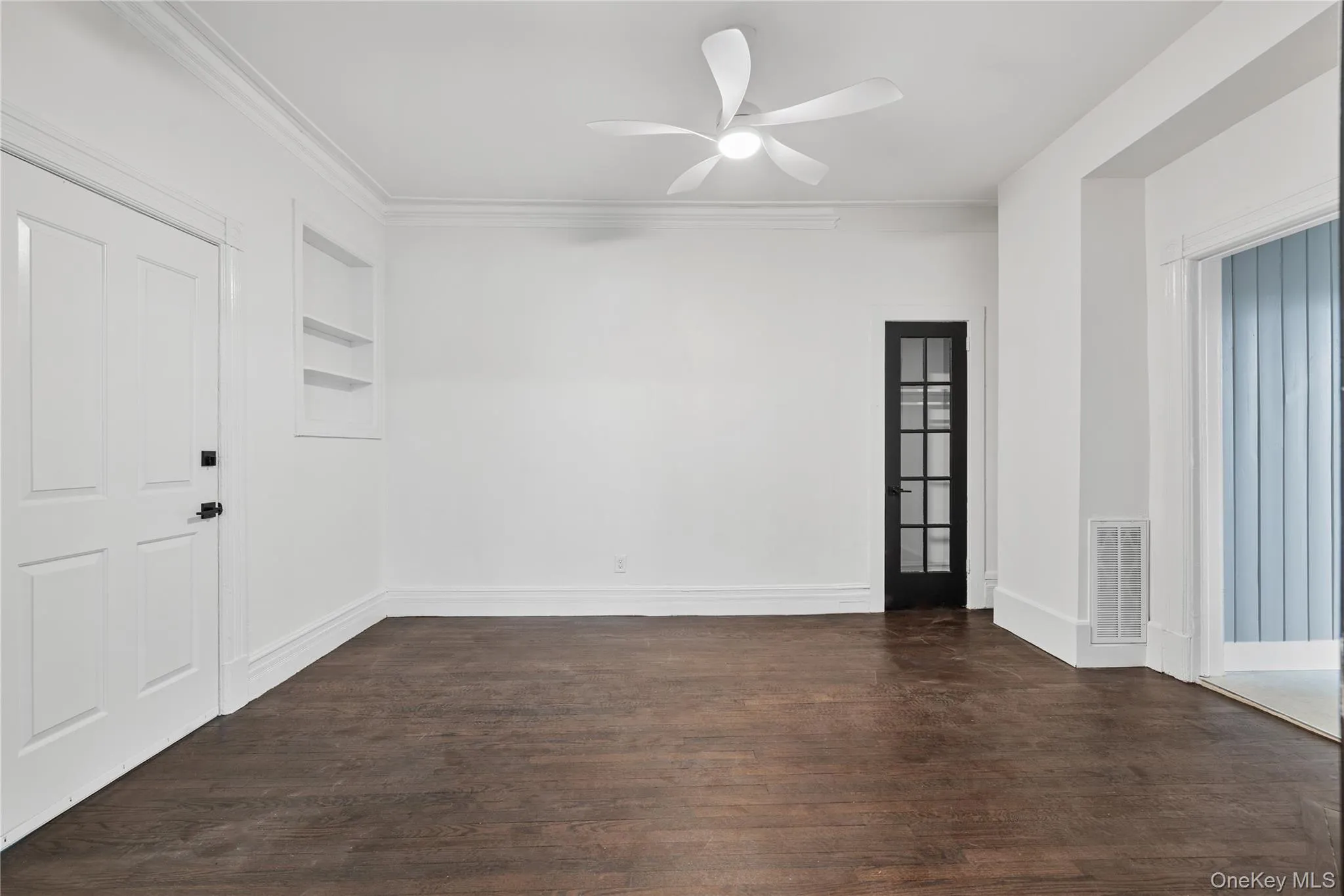 Unfurnished room with visible vents, built in features, ceiling fan, and dark wood finished floors Unfurnished room with visible vents, built in features, ceiling fan, and dark wood finished floors