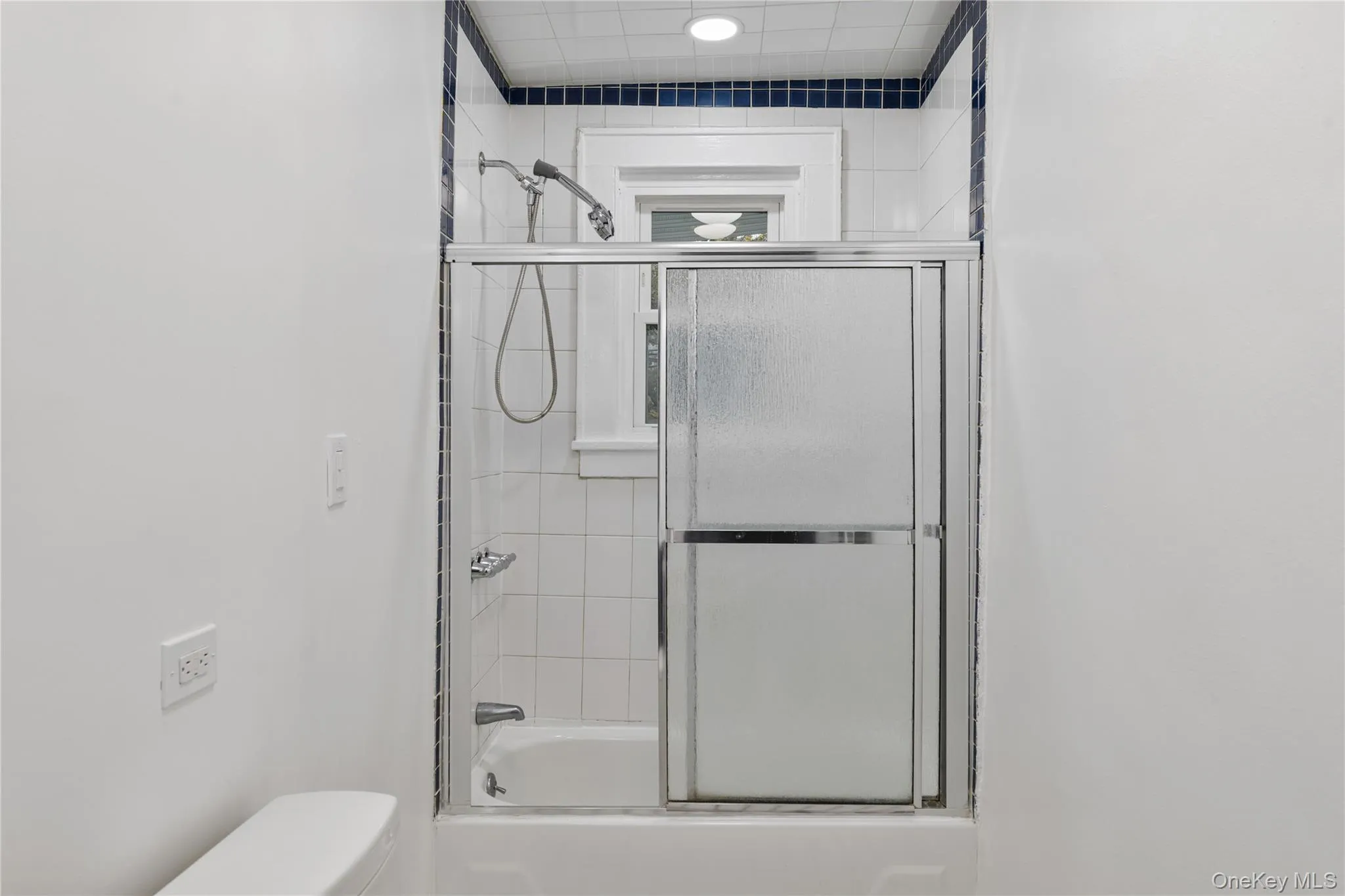 Bathroom with combined bath / shower with glass door and toilet Bathroom with combined bath / shower with glass door and toilet