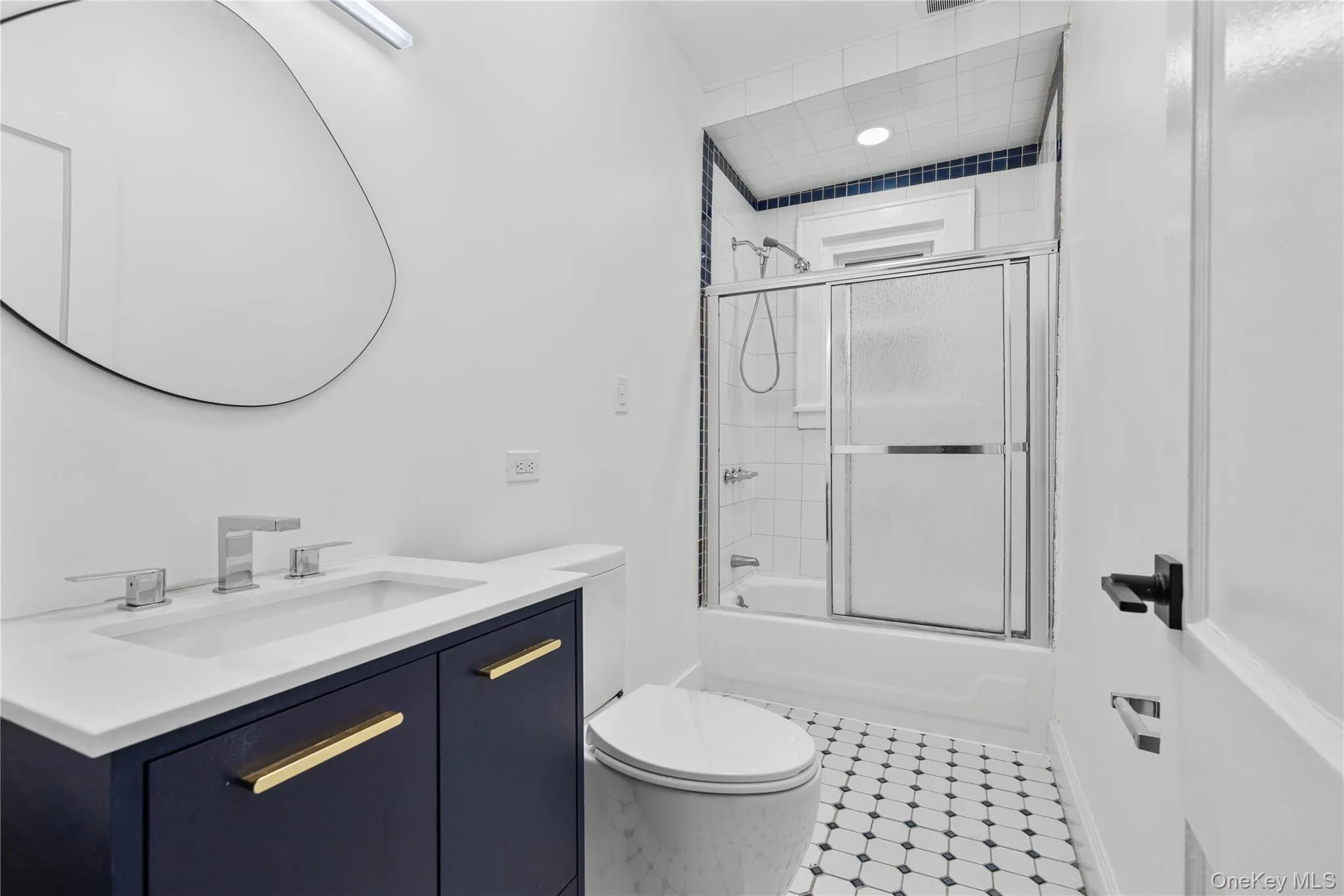 Bathroom with combined bath / shower with glass door, toilet, and vanity Bathroom with combined bath / shower with glass door, toilet, and vanity