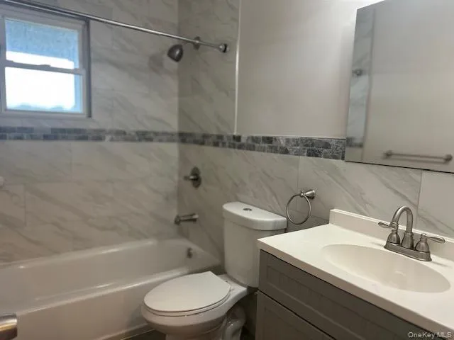 Bathroom with vanity, tile walls, shower / bath combination, and backsplash Bathroom with vanity, tile walls, shower / bath combination, and backsplash