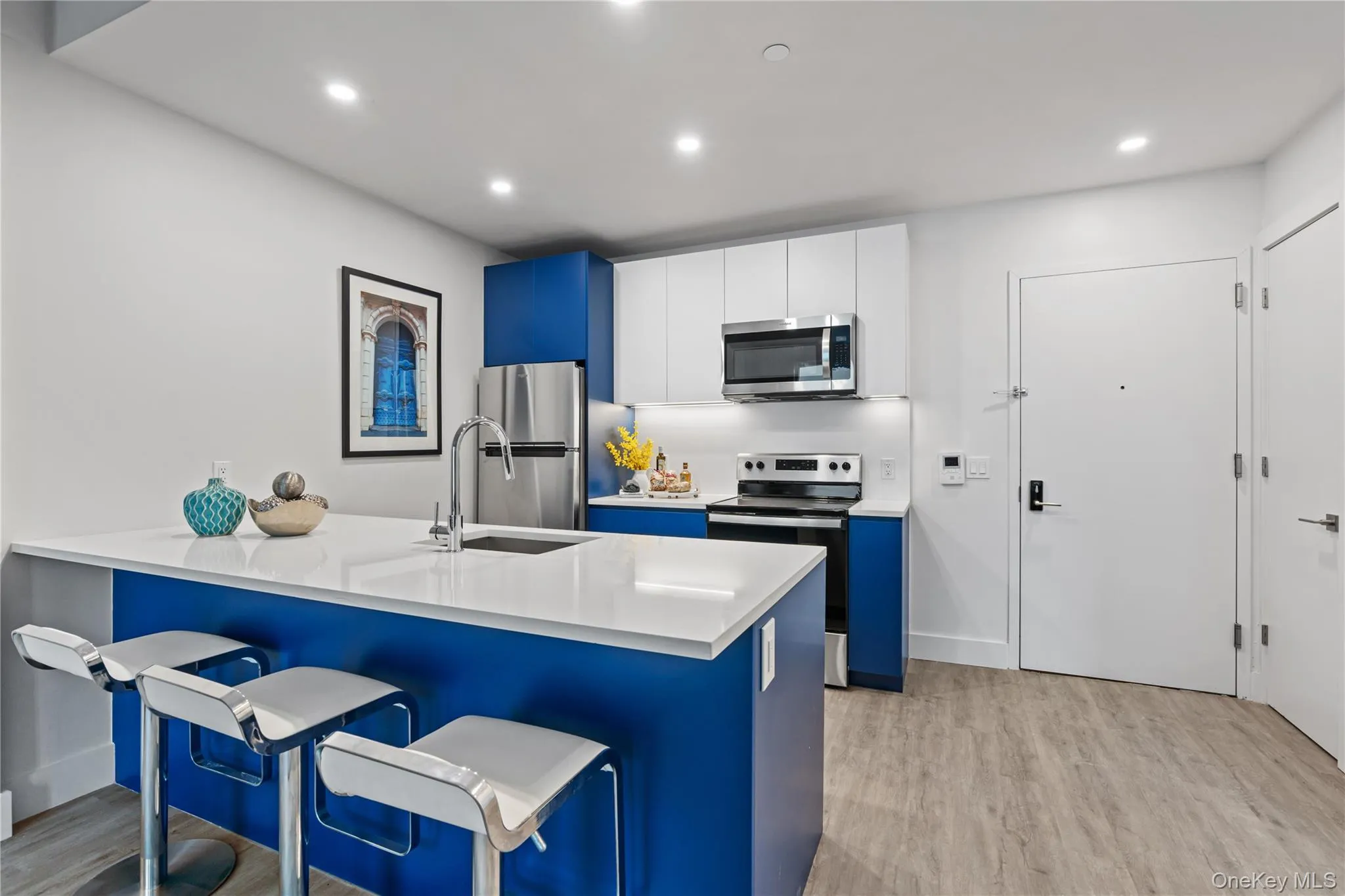 Kitchen with blue cabinetry, a kitchen bar, a peninsula, appliances with stainless steel finishes, and white cabinetry Kitchen with blue cabinetry, a kitchen bar, a peninsula, appliances with stainless steel finishes, and white cabinetry