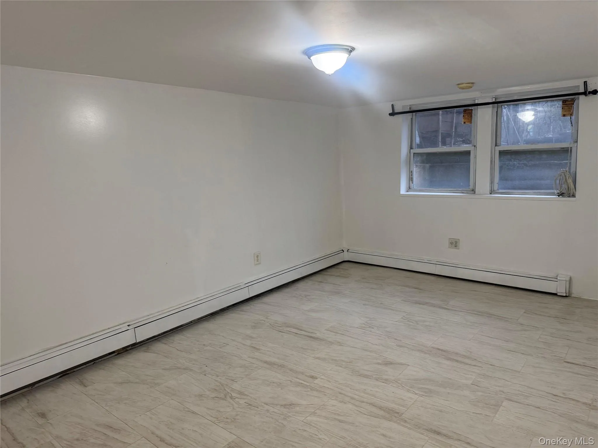 Empty room with a baseboard radiator and light flooring Empty room with a baseboard radiator and light flooring