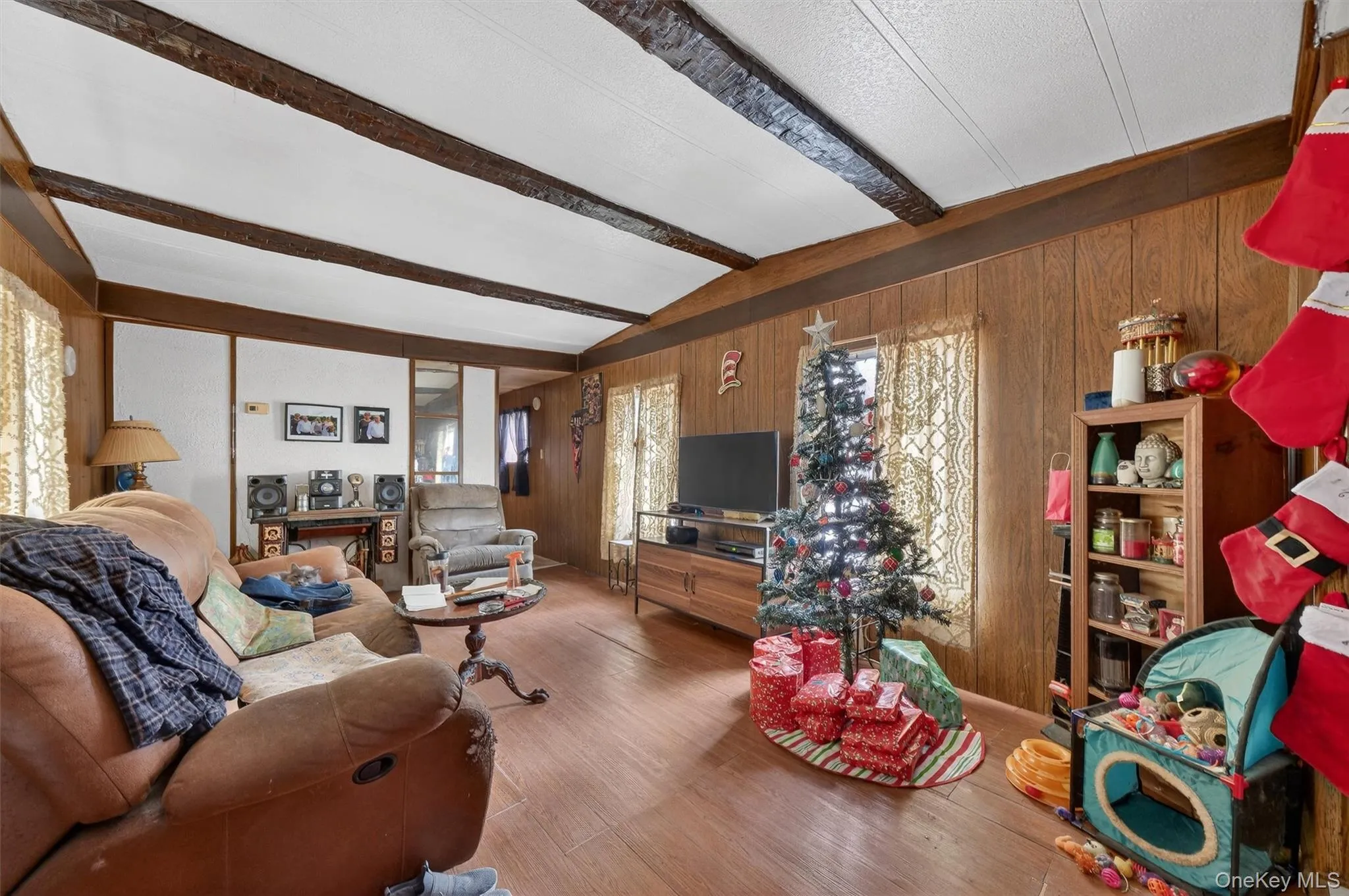 Living room with wooden walls, beamed ceiling, wood finished floors, and plenty of natural light Living room with wooden walls, beamed ceiling, wood finished floors, and plenty of natural light