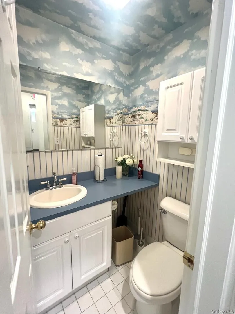 Half bath with vanity, light tile patterned flooring, and wallpapered walls Half bath with vanity, light tile patterned flooring, and wallpapered walls