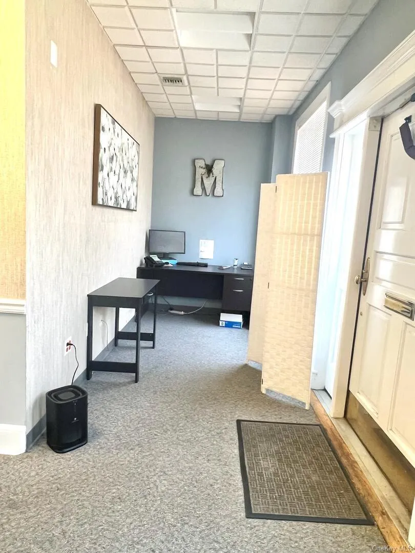 Office area featuring a paneled ceiling and light carpet Office area featuring a paneled ceiling and light carpet