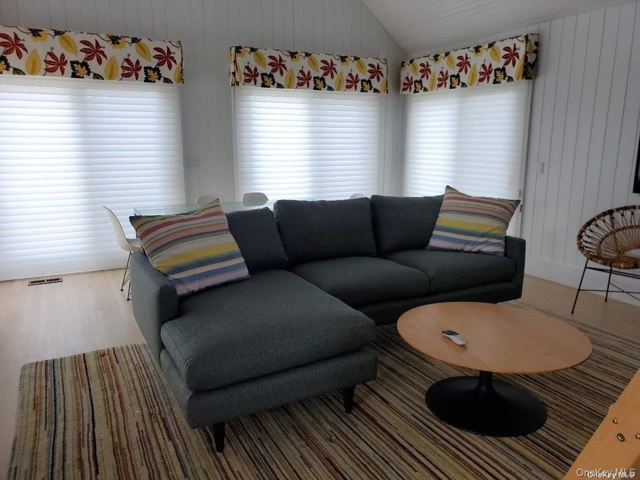 Living room featuring vaulted ceiling, wooden walls, and wood finished floors Living room featuring vaulted ceiling, wooden walls, and wood finished floors