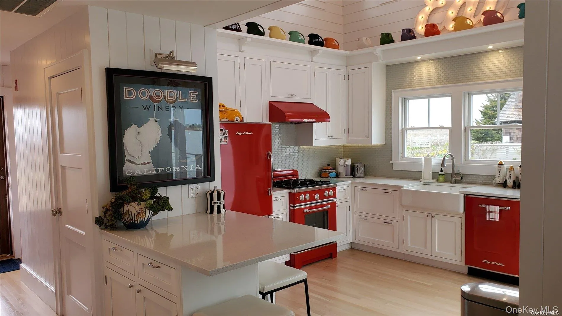 Kitchen with white cabinets, gas range, light wood-style floors, custom range hood, and backsplash Kitchen with white cabinets, gas range, light wood-style floors, custom range hood, and backsplash