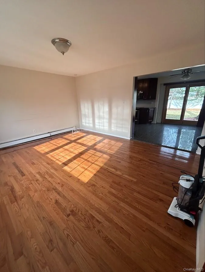 Spare room featuring baseboard heating and wood finished floors Spare room featuring baseboard heating and wood finished floors