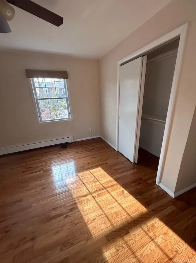 Unfurnished bedroom with baseboard heating, a closet, and light wood-type flooring Unfurnished bedroom with baseboard heating, a closet, and light wood-type flooring
