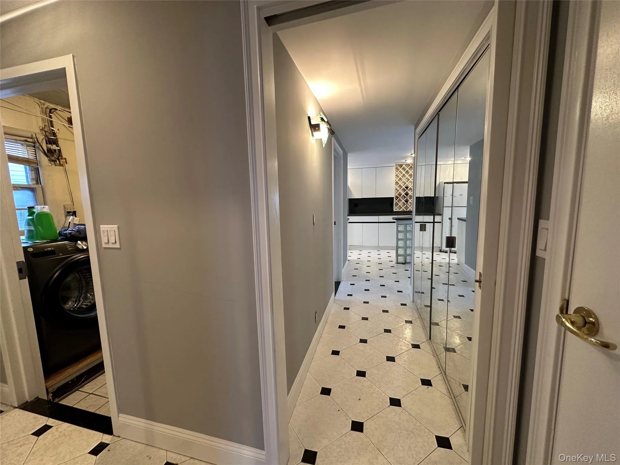 Hallway with washer / clothes dryer and light tile patterned floors Hallway with washer / clothes dryer and light tile patterned floors