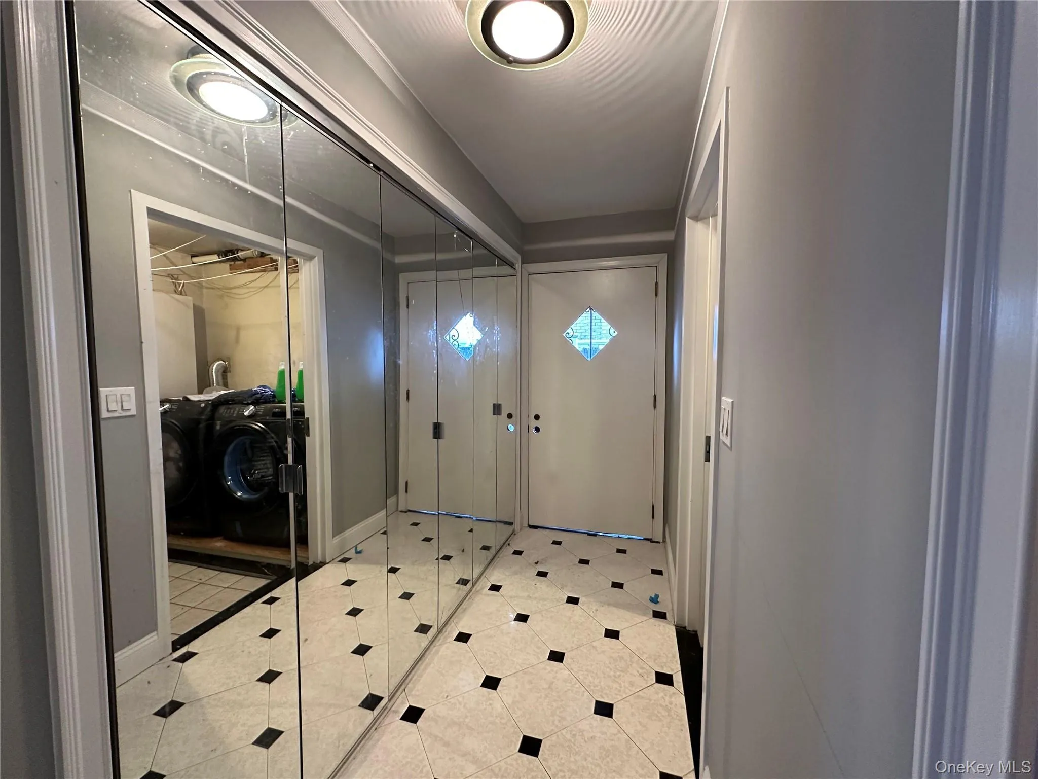 Entrance foyer with light tile patterned floors and washer and clothes dryer Entrance foyer with light tile patterned floors and washer and clothes dryer