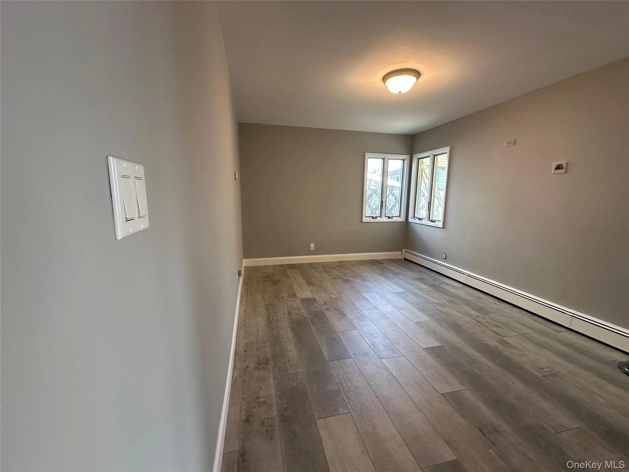 Spare room with hardwood / wood-style floors and a baseboard radiator Spare room with hardwood / wood-style floors and a baseboard radiator