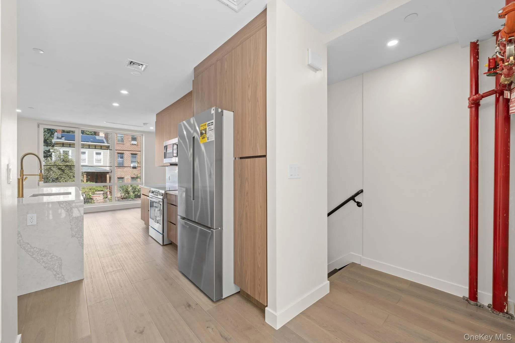 Kitchen with recessed lighting, modern cabinets, stainless steel appliances, light wood-type flooring, and light stone countertops Kitchen with recessed lighting, modern cabinets, stainless steel appliances, light wood-type flooring, and light stone countertops