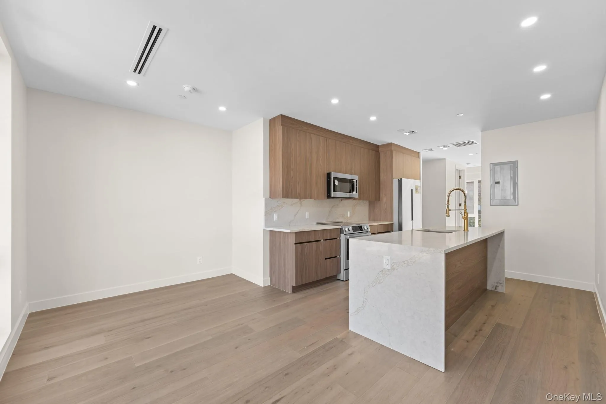 Kitchen featuring modern cabinets, brown cabinetry, light stone counters, stainless steel appliances, and light wood-style floors Kitchen featuring modern cabinets, brown cabinetry, light stone counters, stainless steel appliances, and light wood-style floors