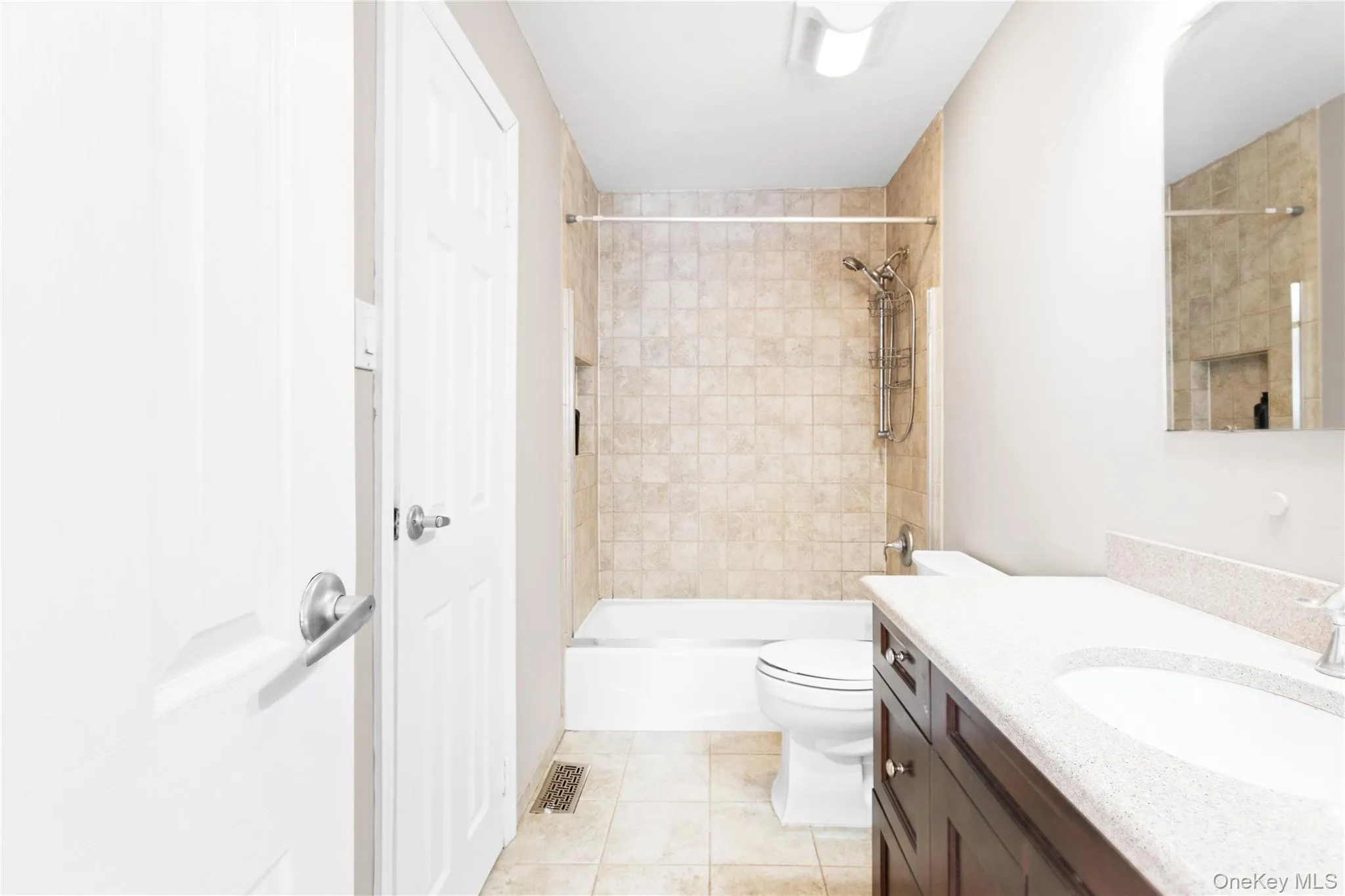 Full bathroom featuring vanity, bathtub / shower combination, and light tile patterned floors Full bathroom featuring vanity, bathtub / shower combination, and light tile patterned floors