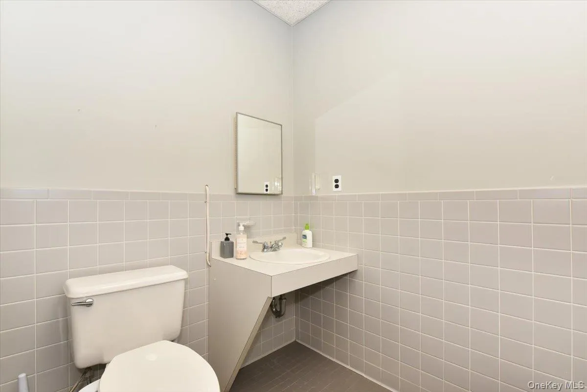 Bathroom with a wainscoted wall and tile walls Bathroom with a wainscoted wall and tile walls