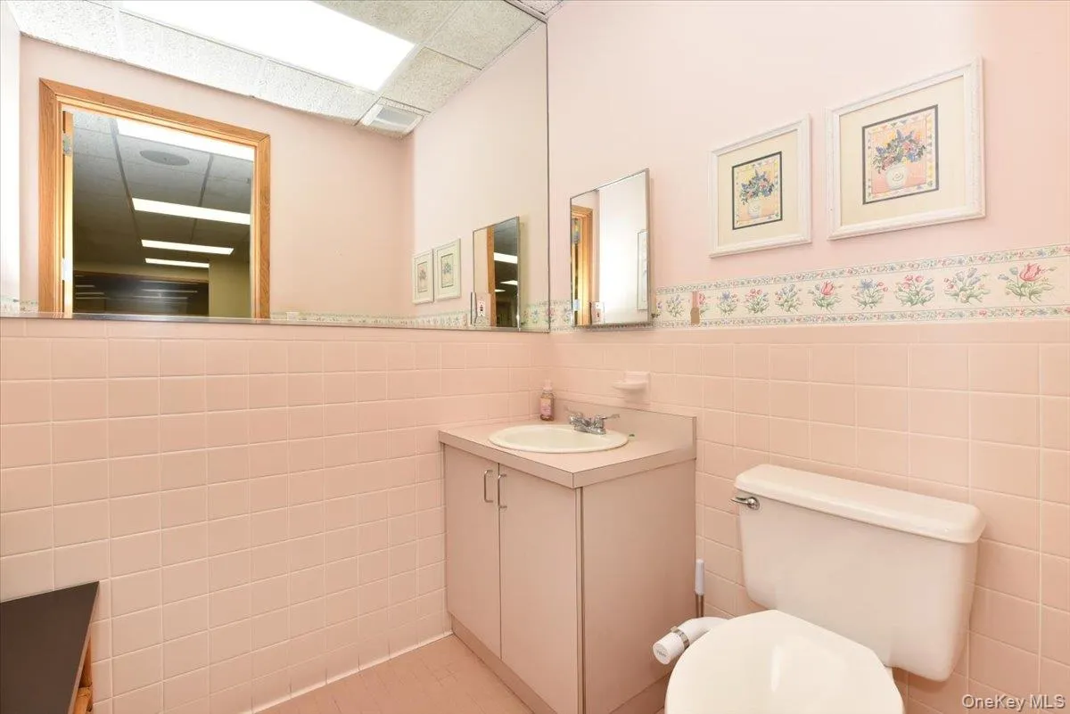 Half bath featuring a wainscoted wall, tile walls, a paneled ceiling, and vanity Half bath featuring a wainscoted wall, tile walls, a paneled ceiling, and vanity