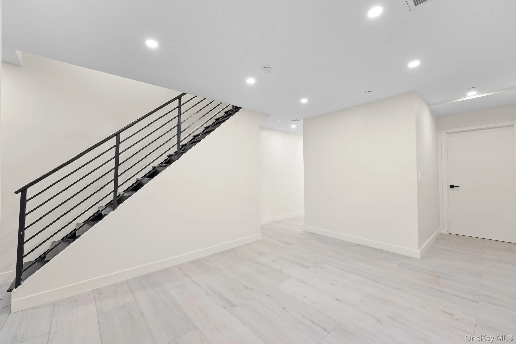 Below grade area with recessed lighting, light wood-style flooring, and stairs Below grade area with recessed lighting, light wood-style flooring, and stairs