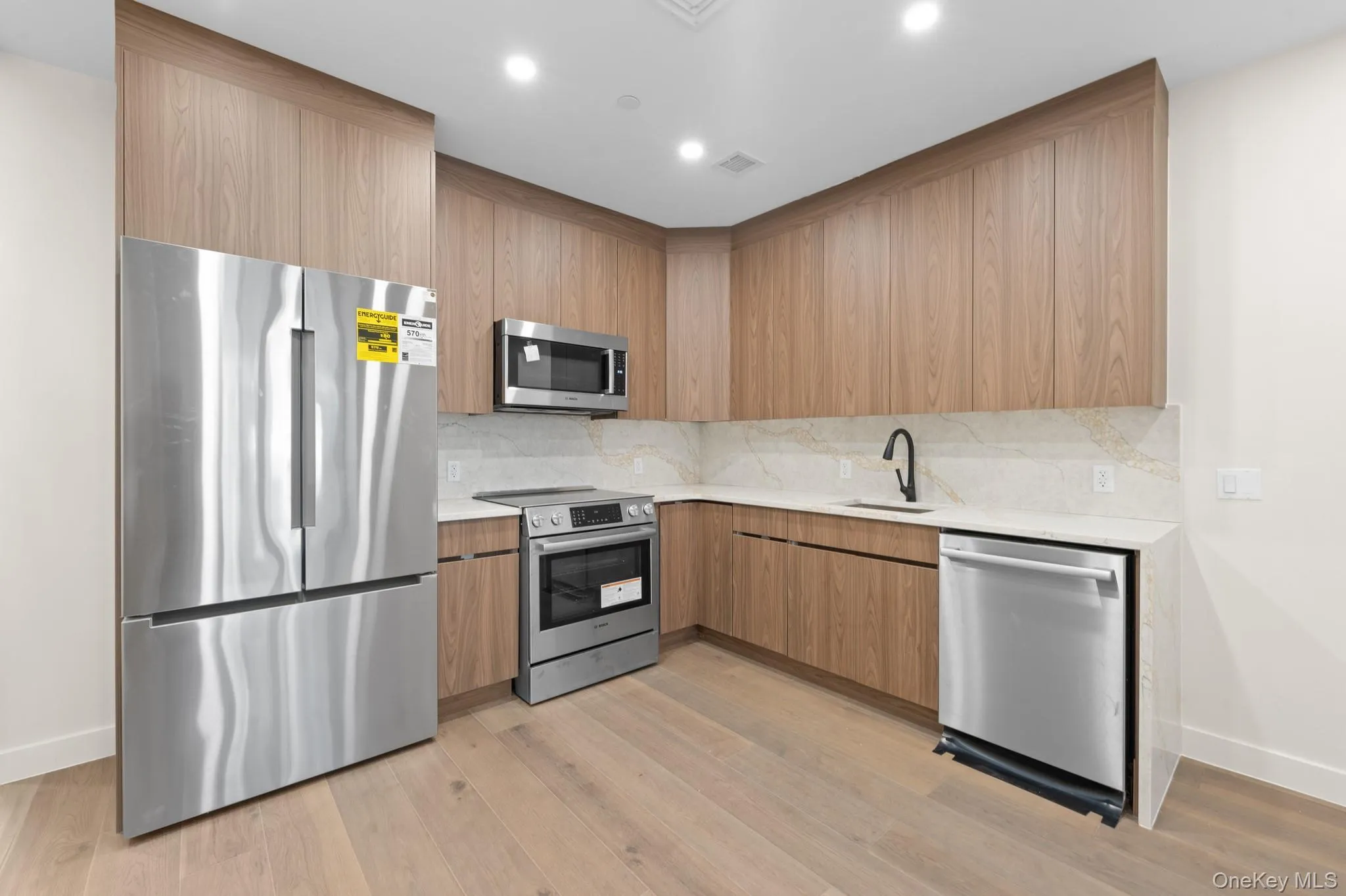 Kitchen featuring modern cabinets, appliances with stainless steel finishes, light stone counters, backsplash, and recessed lighting Kitchen featuring modern cabinets, appliances with stainless steel finishes, light stone counters, backsplash, and recessed lighting