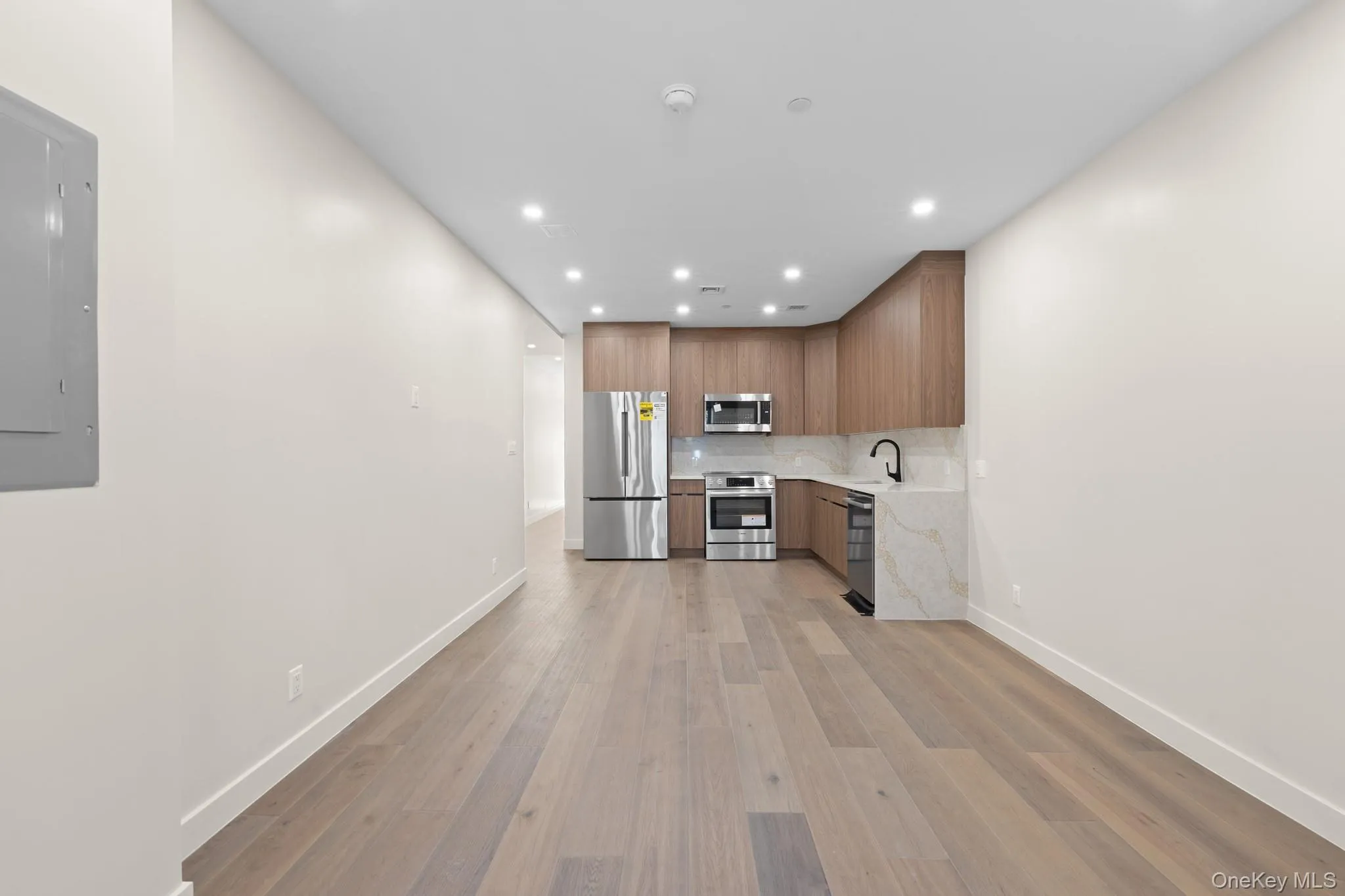 Kitchen with modern cabinets, light wood finished floors, electric panel, stainless steel appliances, and recessed lighting Kitchen with modern cabinets, light wood finished floors, electric panel, stainless steel appliances, and recessed lighting