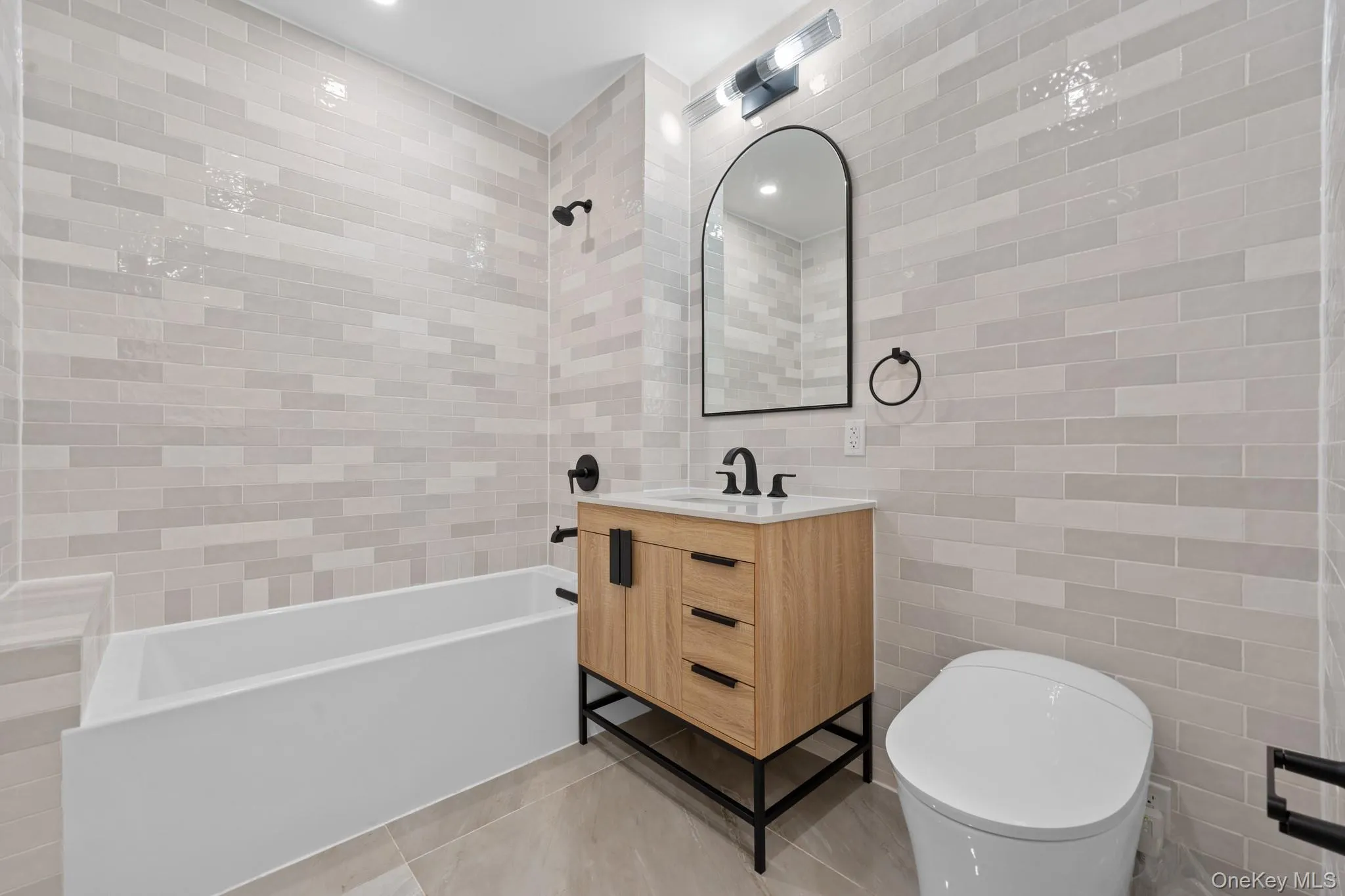 Full bathroom with vanity, shower / bath combination, tile walls, and light tile patterned flooring Full bathroom with vanity, shower / bath combination, tile walls, and light tile patterned flooring
