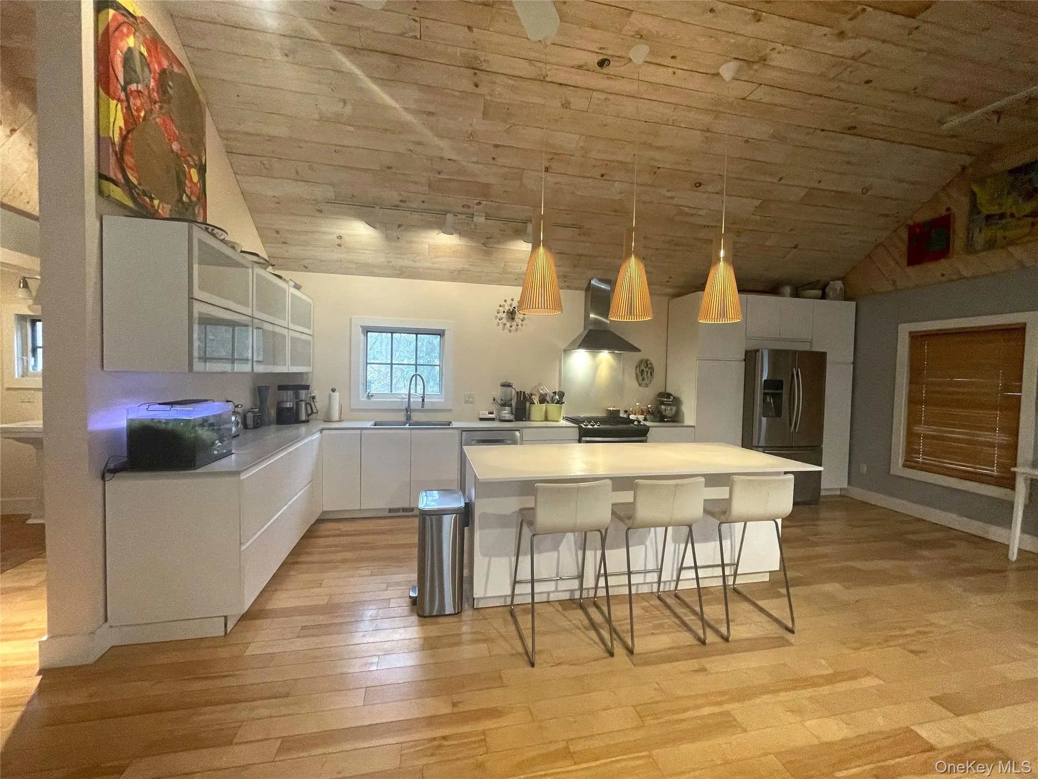 Kitchen with white cabinetry, decorative light fixtures, wooden ceiling, a breakfast bar, and a kitchen island