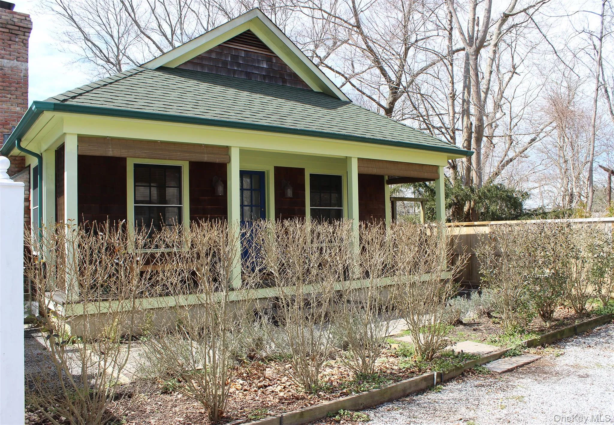 View of front facade with roof with shingles, a chimney, and a porch