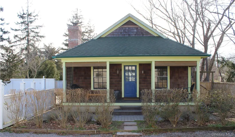 View of front facade with a porch, a chimney, and roof with shingles