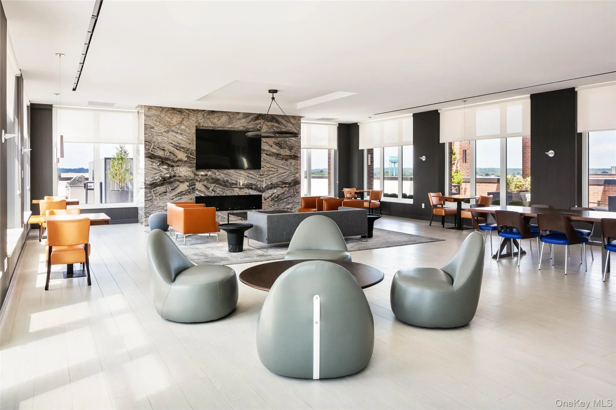 Living area featuring healthy amount of natural light, a wall of windows, and a stone fireplace Living area featuring healthy amount of natural light, a wall of windows, and a stone fireplace