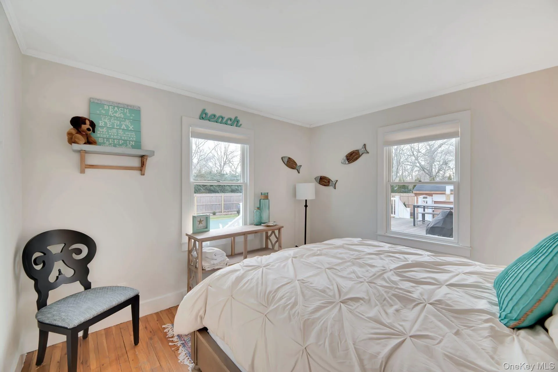 Bedroom with multiple windows, light wood-style flooring, and ornamental molding Bedroom with multiple windows, light wood-style flooring, and ornamental molding