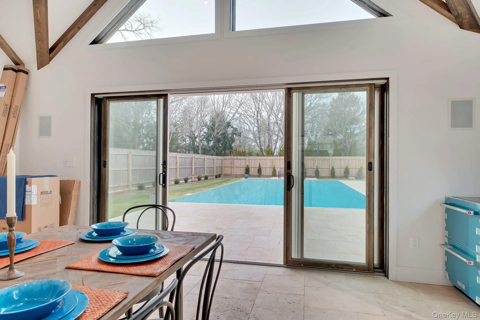 Dining area featuring healthy amount of natural light, stone tile floors, beamed ceiling, and high vaulted ceiling Dining area featuring healthy amount of natural light, stone tile floors, beamed ceiling, and high vaulted ceiling