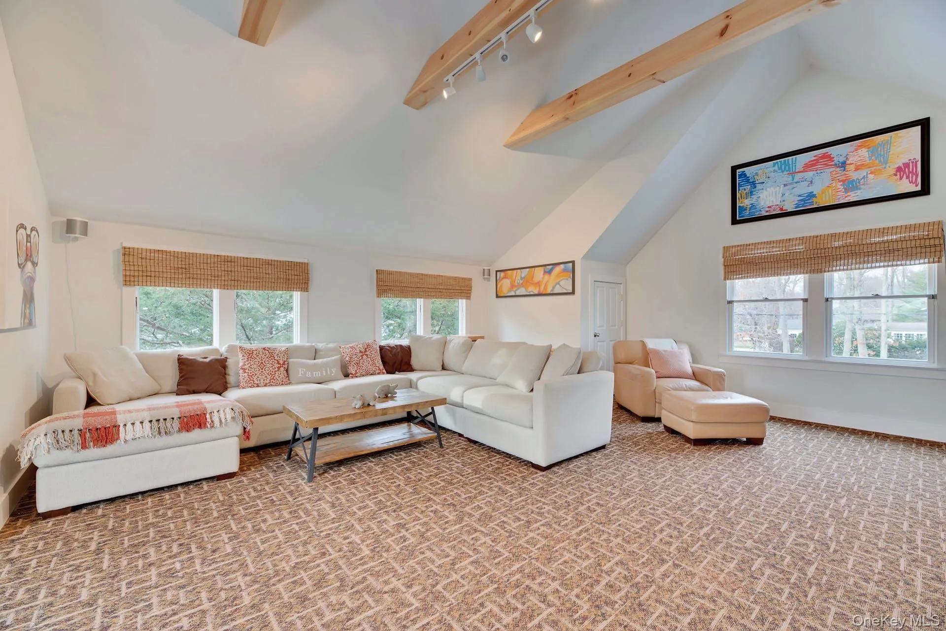 Living room with beamed ceiling, high vaulted ceiling, track lighting, and carpet Living room with beamed ceiling, high vaulted ceiling, track lighting, and carpet