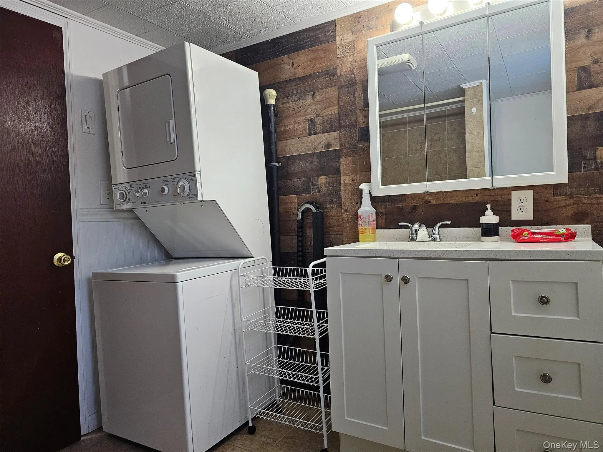 Washroom featuring wood walls and stacked washer and clothes dryer Washroom featuring wood walls and stacked washer and clothes dryer