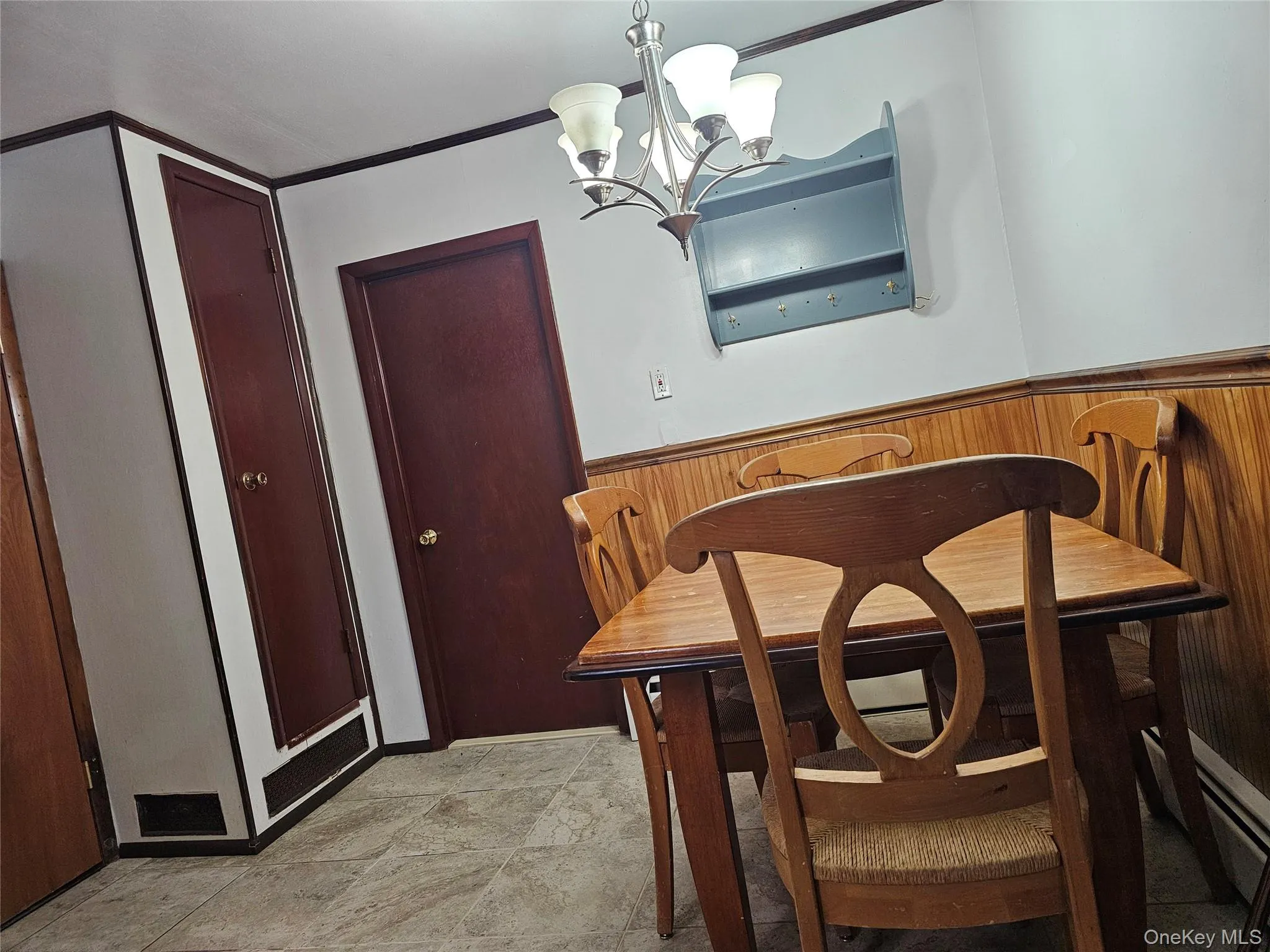 Dining area featuring a chandelier, wainscoting, and wooden walls Dining area featuring a chandelier, wainscoting, and wooden walls