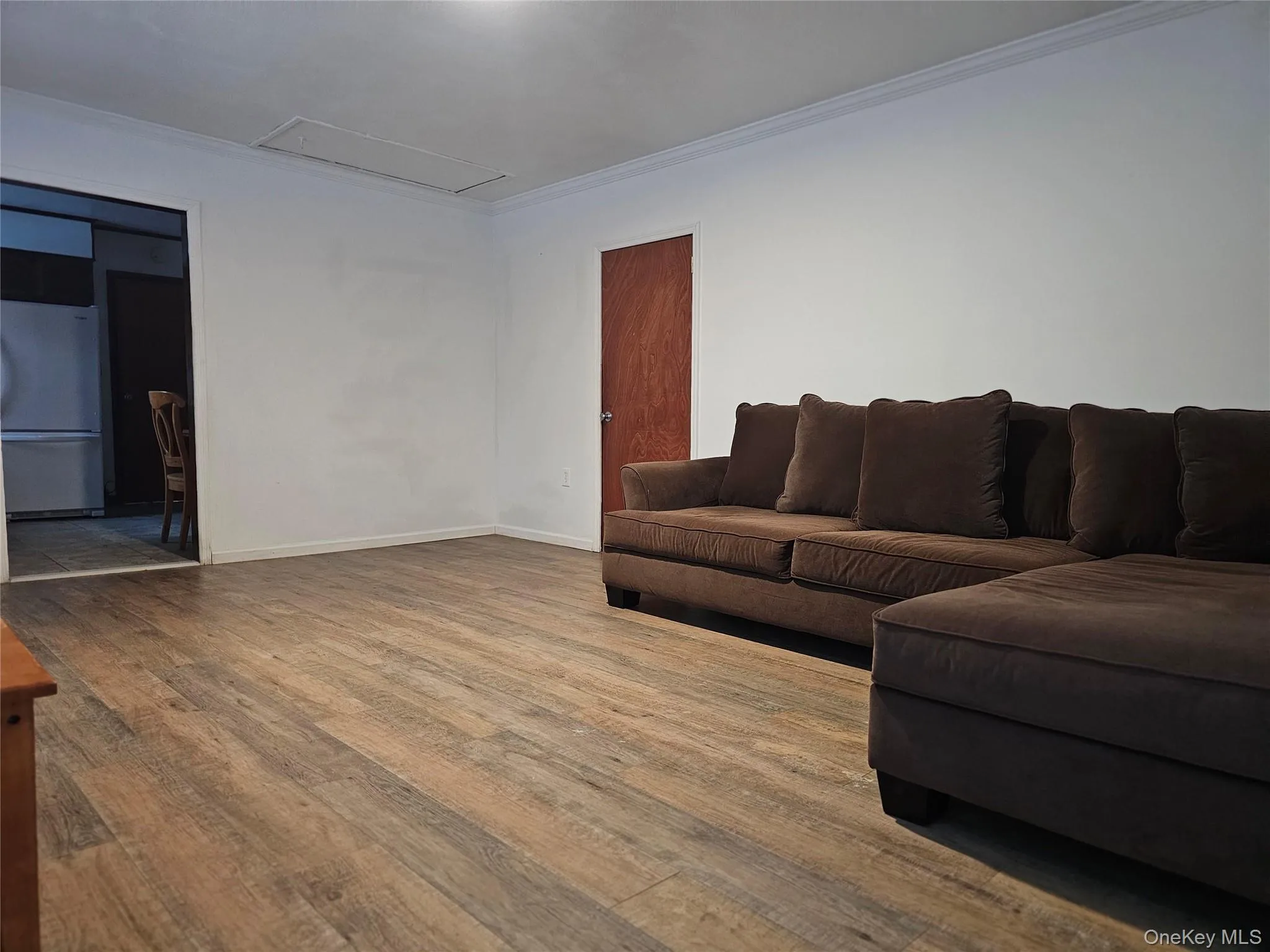 Living room with wood finished floors, attic access, and ornamental molding Living room with wood finished floors, attic access, and ornamental molding