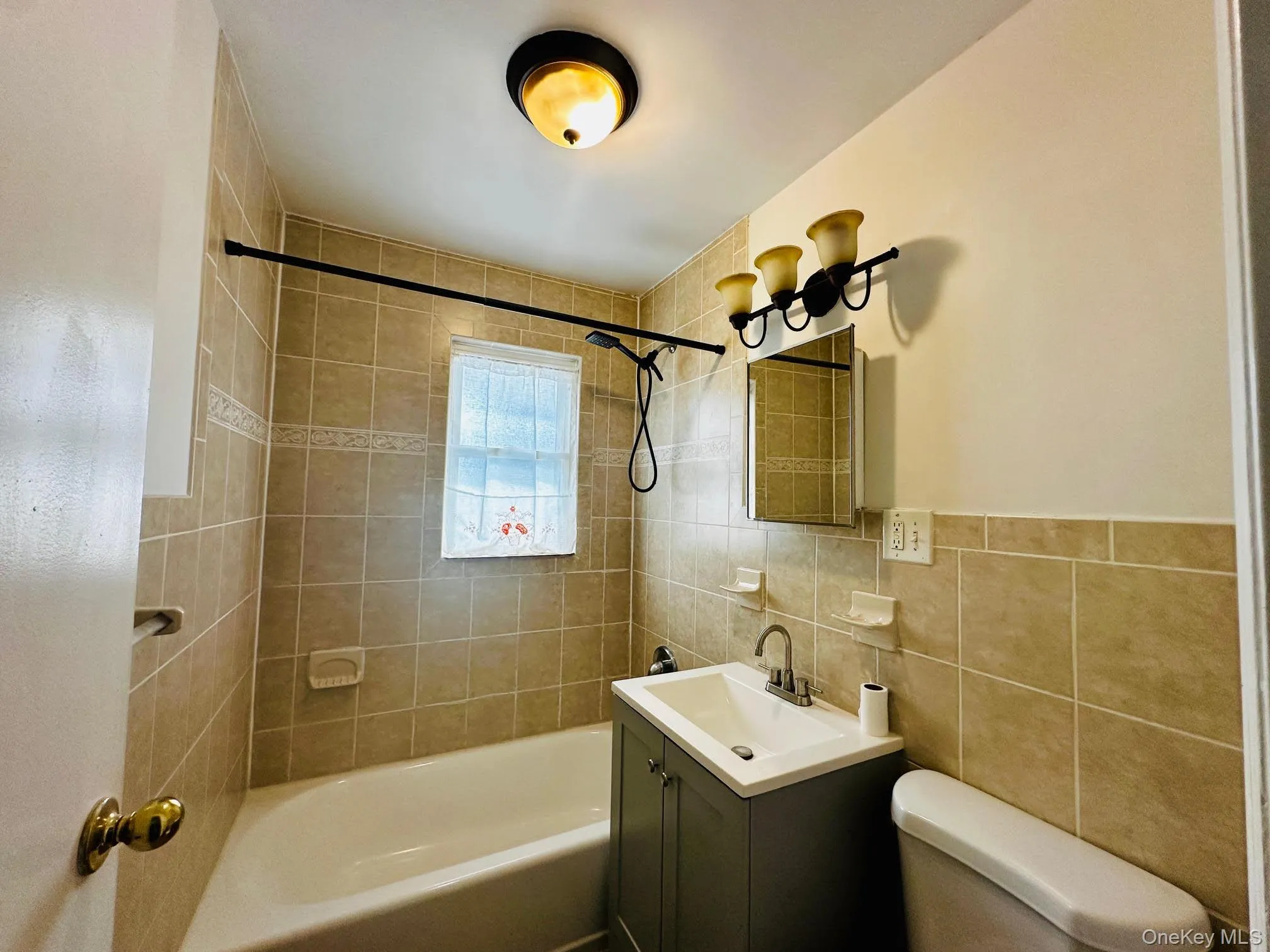 Bathroom featuring vanity, shower / tub combination, and tile walls Bathroom featuring vanity, shower / tub combination, and tile walls
