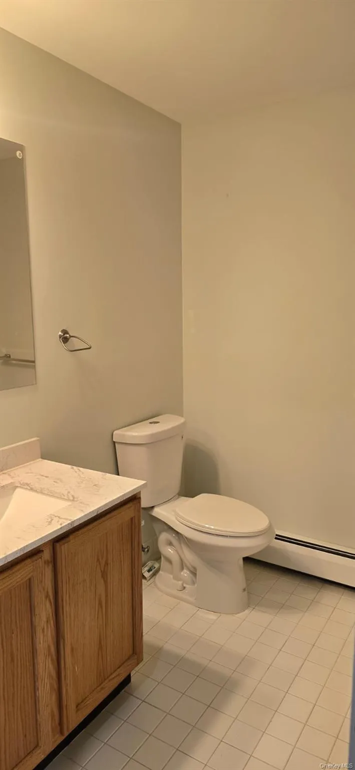 Half bath featuring baseboard heating, vanity, and light tile patterned floors Half bath featuring baseboard heating, vanity, and light tile patterned floors