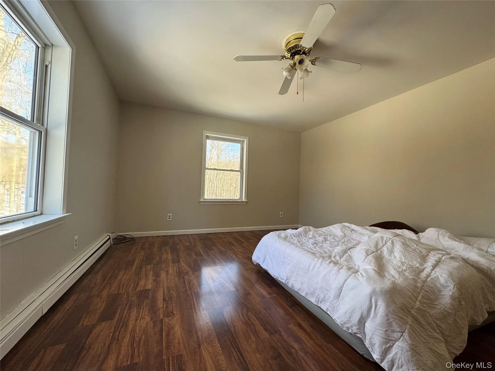 Bedroom with baseboard heating, dark wood-type flooring, and a ceiling fan Bedroom with baseboard heating, dark wood-type flooring, and a ceiling fan