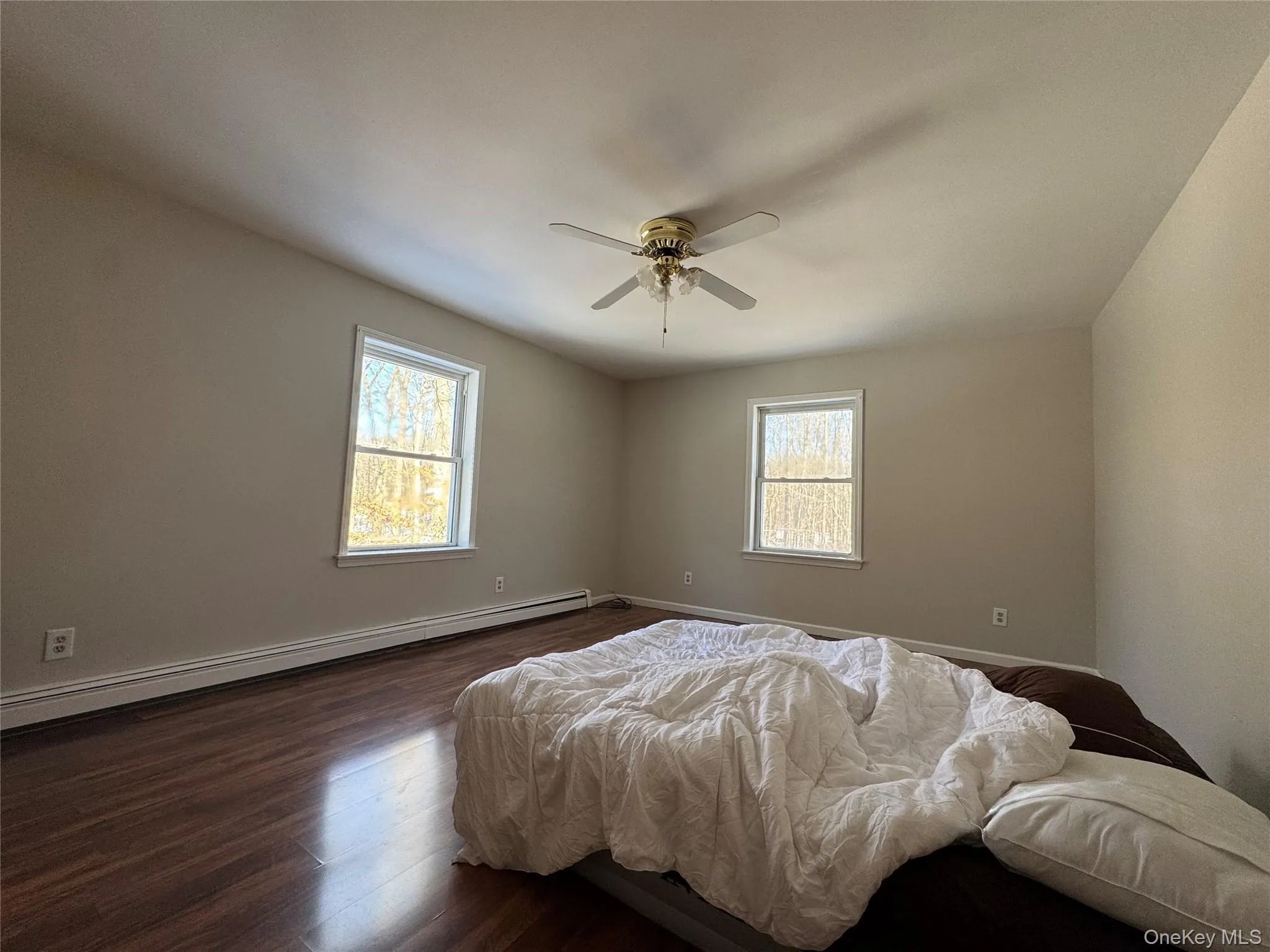 Bedroom with dark wood-style flooring, a baseboard radiator, and a ceiling fan Bedroom with dark wood-style flooring, a baseboard radiator, and a ceiling fan