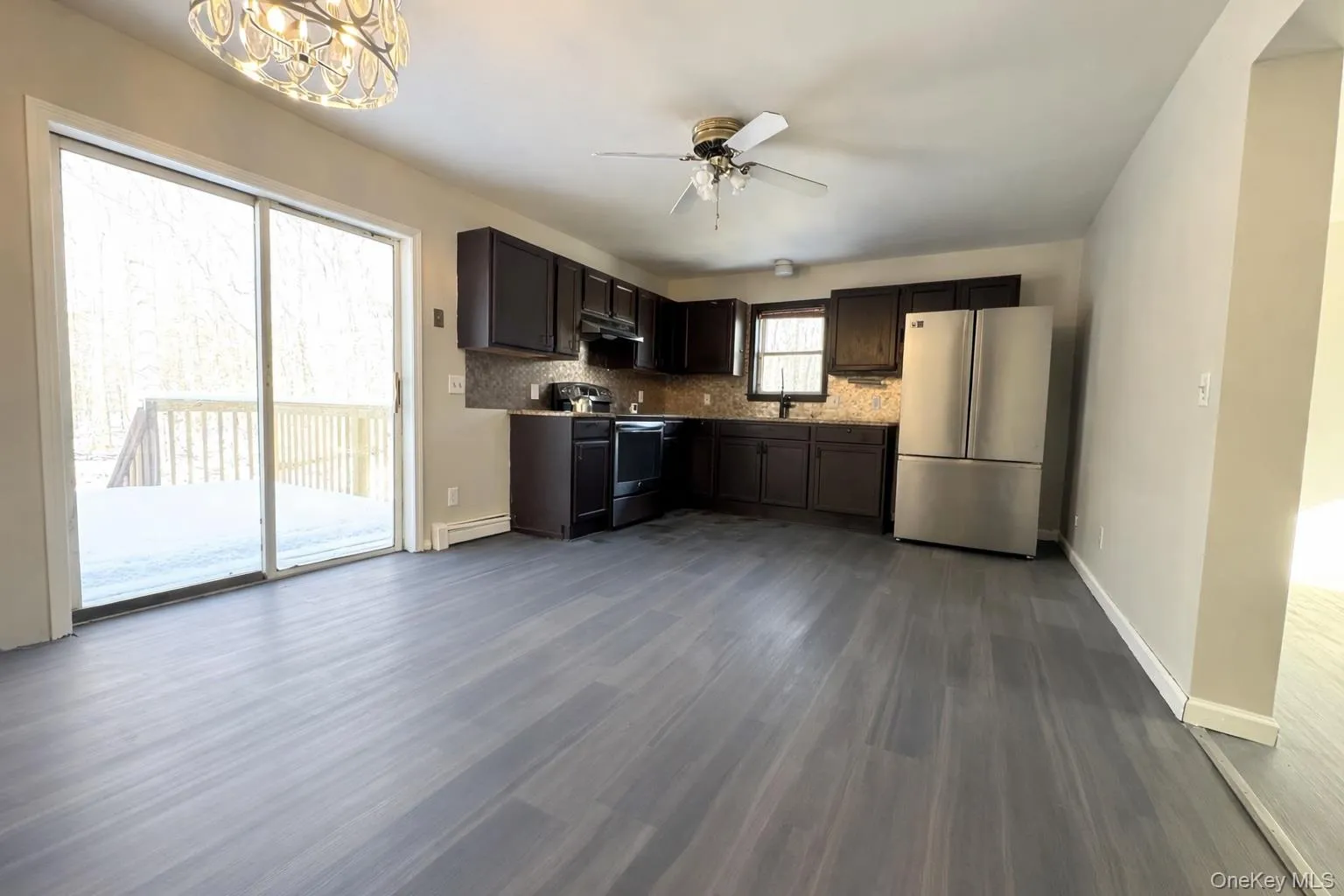 Kitchen with appliances with stainless steel finishes, dark wood-style floors, dark brown cabinetry, a ceiling fan, and a baseboard heating unit Kitchen with appliances with stainless steel finishes, dark wood-style floors, dark brown cabinetry, a ceiling fan, and a baseboard heating unit