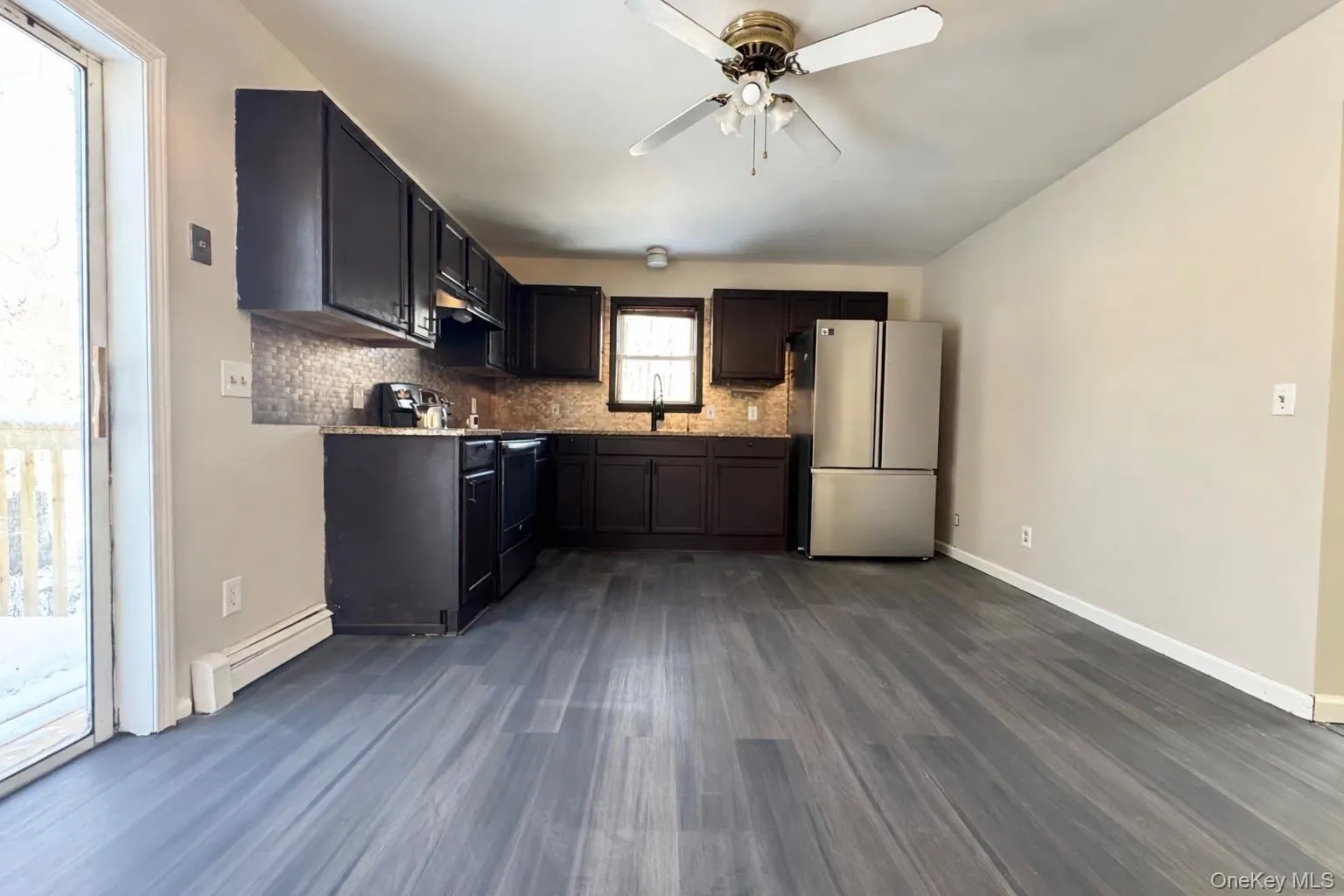 Kitchen with stainless steel appliances, a baseboard radiator, dark wood-type flooring, ceiling fan, and tasteful backsplash Kitchen with stainless steel appliances, a baseboard radiator, dark wood-type flooring, ceiling fan, and tasteful backsplash