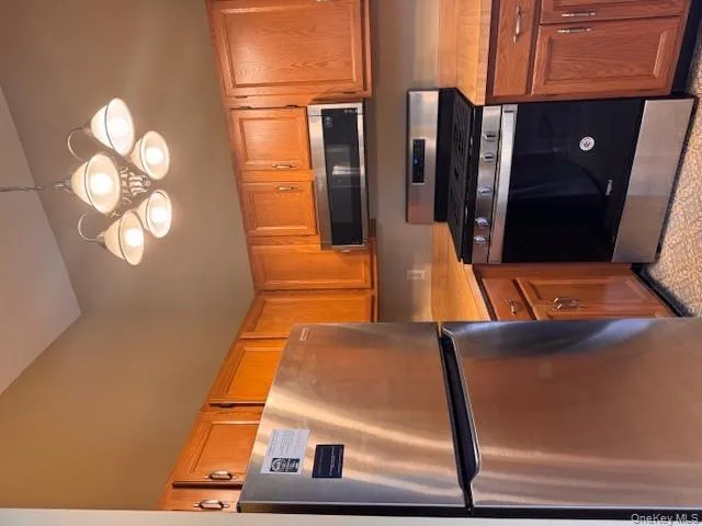 Kitchen with appliances with stainless steel finishes, light countertops, pendant lighting, and brown cabinets Kitchen with appliances with stainless steel finishes, light countertops, pendant lighting, and brown cabinets