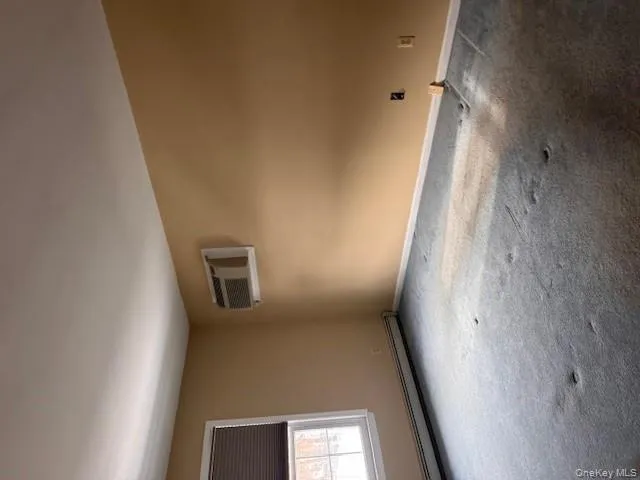 Carpeted spare room featuring baseboard heating and a wall unit AC Carpeted spare room featuring baseboard heating and a wall unit AC