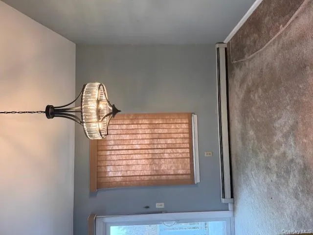 Unfurnished dining area with carpet floors, a baseboard heating unit, and a chandelier Unfurnished dining area with carpet floors, a baseboard heating unit, and a chandelier